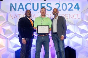 UConn Dining Executive Director Michael White (center) accepting the award on stage at the NACUFS National Conference