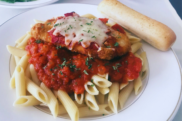 plate of pasta, sauce, chicken parm and breadstick