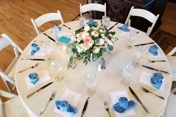 table set with white linens blue napkins and menus
